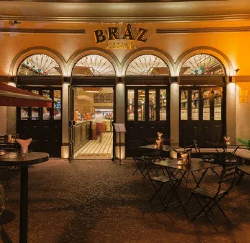 Fachada iluminada da Bráz Pizzaria, em Moema, São Paulo, com mesas na calçada, na vizinhança do Alameda Mará.