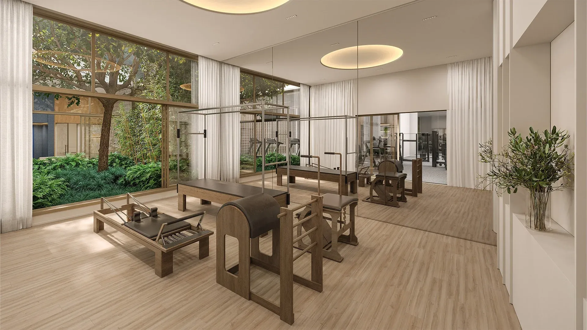 Sala de pilates indoor no térreo do Alameda Mará, Gamaro, em Moema, com aparelhos Cadillac e Reformer e vista para o paisagismo.